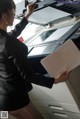 A woman in a black suit is using a printer.