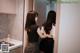 A woman standing in front of a mirror in a kitchen.