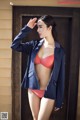 A woman in a blue jacket and red bikini posing for a picture.