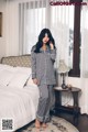 A woman standing in front of a bed in a bedroom.