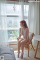 A woman sitting on a chair in front of a window.