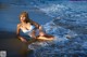 A woman in a white bathing suit sitting on the beach.