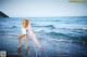 A woman in a white bathing suit standing in the ocean.