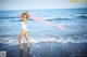 A woman in a white bathing suit standing on the beach.