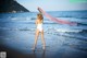 A woman in a white bathing suit standing on the beach.