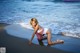 A woman in a pink and white bathing suit on the beach.