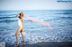 A woman in a white bathing suit standing in the ocean.