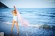 A woman in a white bathing suit standing on the beach.