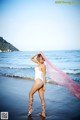 A woman in a white bathing suit standing on a beach.