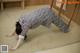 A woman in a black and white patterned pajamas doing a yoga pose.