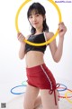 A woman in a black top and red shorts holding a yellow hula hoop.