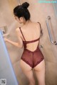 A woman in a burgundy lingerie standing in a shower.