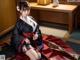 A woman in a black and red kimono sitting on the floor.