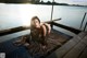 A woman sitting on a dock next to a body of water.