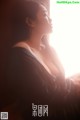 A woman sitting in front of a window looking out the window.