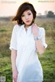 A woman in a white dress standing in a field.