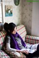 A woman sitting on a couch reading a book.