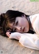 A woman laying on the sand with her head resting on her hands.