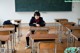 A woman sitting at a desk in a classroom.