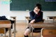 A woman sitting at a desk in a classroom.