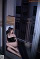 A woman sitting on a balcony next to a washing machine.