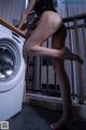 A woman in a black bikini standing next to a washing machine.