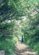 A woman in a blue dress walking down a path in the woods.