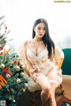 A woman sitting on a chair next to a Christmas tree.