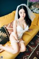 A woman sitting on a yellow couch wearing a white lingerie.