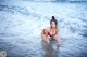 A woman in a red bikini is standing in the water.