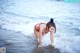 A woman in a red bikini standing in the ocean.