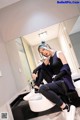 A woman sitting on top of a sink in a bathroom.