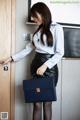 A woman in a white shirt and black skirt holding a blue briefcase.