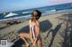 A woman in a bathing suit sitting on a beach.