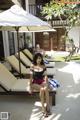 A woman in a bathing suit sitting on a lounge chair.