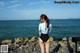 A woman standing on a rocky beach next to the ocean.