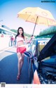 A woman holding an umbrella standing next to a car.