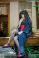 A woman in a kimono sitting on a stone ledge.