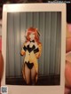 A person holding up a polaroid photo of a woman dressed as a bunny.