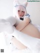 A woman in a white cat costume is sitting on a bed.