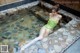 A woman in a green bathing suit sitting in a hot tub.