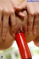 A woman is holding a red dildo in her mouth.