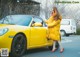 A woman in a yellow coat standing next to a yellow car.