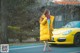 A woman in a yellow coat is standing next to a yellow car.