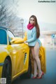 A woman standing next to a yellow sports car.