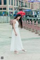 A woman in a white dress is walking down the street.