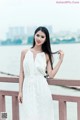 A woman in a white dress standing on a wooden bridge.