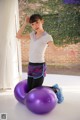 A young woman sitting on a purple exercise ball.