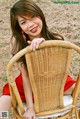 A woman in a red dress sitting on a wicker chair.