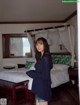 A woman standing in front of a bed in a bedroom.